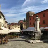 Piazza di Montecatini Alto, con tavolini all'aperto e un monumento. Un assaggio di cosa vedere a Montecatini Alto.