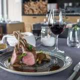 Carré d'agnello al forno con funghi e un bicchiere di vino rosso, un abbinamento perfetto per un pasto speciale.