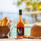 Un bicchiere di vino dolce dell'Elba, grissini croccanti e un cappello di paglia, perfetti per un aperitivo al mare.