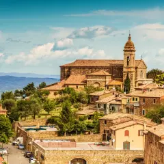 Panoramica di Montalcino, borgo medievale toscano con la sua imponente cattedrale e le case in pietra, immerso nel verde delle colline.