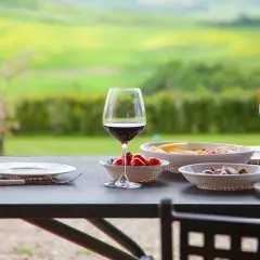 Un bicchiere di vino rosso e stuzzichini su un tavolo con vista sui chianti vineyards.