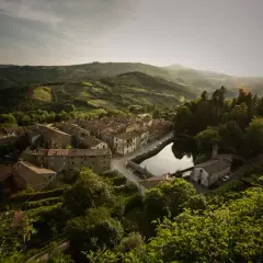 Peschiera Santa Fiora, un borgo toscano incastonato tra colline verdi, con case in pietra e un laghetto che riflette il cielo.