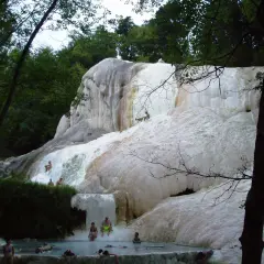 Cascate di travertino a Santa Fiora Terme, con persone che si rilassano nelle acque termali.