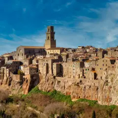 Il centro storico di Pitigliano, arroccato su una rupe tufacea, con le sue case antiche e la torre campanaria che domina il paesaggio.