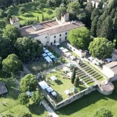 Mercato all'aperto nel parco dell'Acciaiolo, con bancarelle, persone e un edificio storico circondato da alberi.