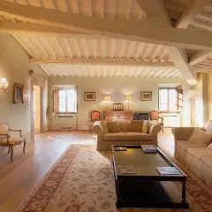 Accogliente salotto con camino acceso nel castello di Pomino. Travi a vista, tappeti orientali e mobili d'epoca creano un'atmosfera calda e raffinata.