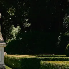 Statua romana domina una scalinata nei **Horti Leonini**. Giardini curati e alberi ombrosi creano un'atmosfera serena.