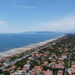 Vista aerea della costa toscana, dove si trova Forte dei Marmi, con spiagge attrezzate, mare blu e un fitto tessuto urbano.