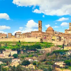Panoramica di Volterra, con torri medievali e case in pietra su una collina verde. Molte cose da fare a Volterra, tra cui esplorare il centro storico.