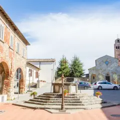 Piazza di Civitella Val di Chiana con pozzo antico, chiesa romanica e case in pietra.