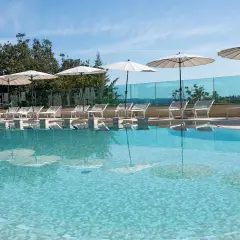 Piscina con lettini e ombrelloni, riflessi sull'acqua cristallina. Un angolo di relax a **Abbadia San Salvatore terme**.