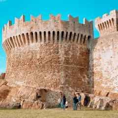 Antica fortezza in pietra, uno dei borghi vicino Livorno, con una famiglia che passeggia sull'erba.