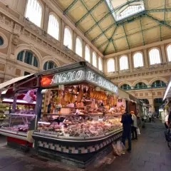 Mercato coperto con banchi di salumi e formaggi, un angolo del buon gusto tra i più bei mercati di Toscana.