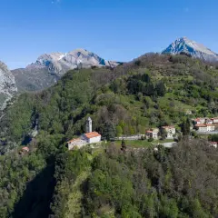 Sant'Anna di Stazzema: un borgo tra monti verdi e cielo azzurro. La chiesa domina il paesaggio, un luogo da scoprire.