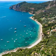Baia con acque cristalline e numerose barche al largo di Porto Santo Stefano.
