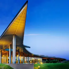 La tenuta ammiraglia Frescobaldi, con la sua architettura moderna illuminata, si staglia contro il cielo serale. Le recensioni lodano questo luogo.