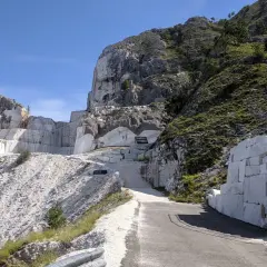 Un imponente passo del vestito di marmo bianco si erge su un fianco della montagna, con blocchi grezzi e una scala scavata nella roccia.