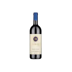 A bottle of Sassicaia wine with a blue cap and a cream-colored label featuring a compass rose.