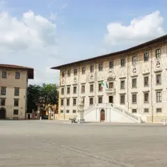 La **piazza dei Cavalieri** a Pisa, con i suoi palazzi storici e la scalinata monumentale, sotto un cielo nuvoloso.