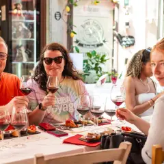Amici brindano a una degustazione vini a Pisa, assaporando sapori toscani con un bicchiere di rosso.
