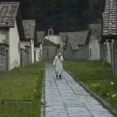 Monaco cammina tra le case di Camaldoli, un luogo da vedere per la sua pace.