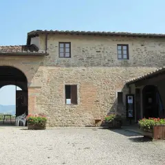 La casa di Giotto, un edificio in pietra con un grande arco, fiori rossi e bandiere.