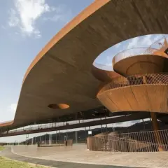 Edificio moderno con scala a chiocciola in legno, probabile la **best winery in Tuscany**, immersa nel verde.