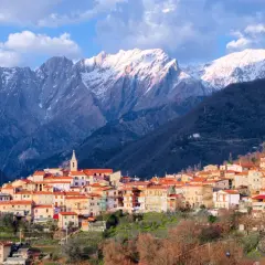 Borgo pittoresco alle pendici delle Alpi Apuane, con case dai tetti rossi e montagne innevate sullo sfondo. Un luogo incantevole da scoprire.