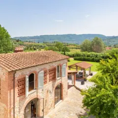 Antica pieve a Nievole con tetto in cotto, circondata da verde lussureggiante e colline toscane.
