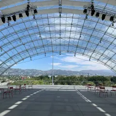 Spazi all'aperto del museo de la academia, con sedie rosse disposte e vista sulle colline di Los Angeles sotto una struttura a volta in vetro.
