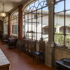 Interno elegante della villa Macchi con mobili d'epoca, grandi finestre ad arco e vista sul cortile verdeggiante.