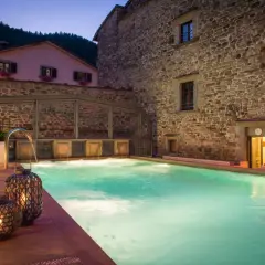 Piscina termale illuminata di notte, con cascate d'acqua e lanterne decorative. Un'oasi di relax nelle terme vicino Arezzo.