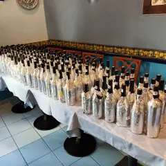 Many wine bottles wrapped in foil, lined up on a table for a tasting.
