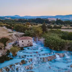 Cascate termali con acqua azzurra e un vecchio mulino, un'oasi di relax che ricorda le terme a Firenze.