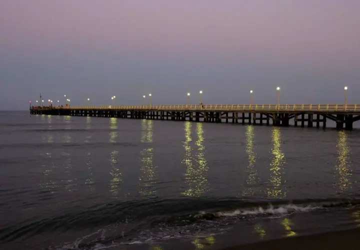 Il pontile di Forte dei Marmi illuminato al crepuscolo, con le luci che si specchiano sul mare calmo.