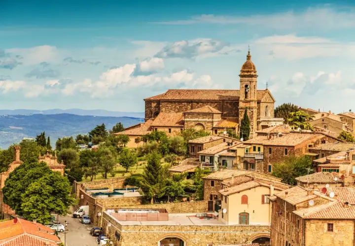 Panoramica di Montalcino, borgo medievale toscano con la sua imponente cattedrale e le case in pietra, immerso nel verde delle colline.