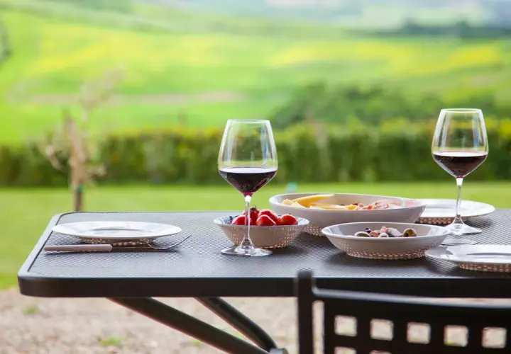 Un bicchiere di vino rosso e stuzzichini su un tavolo con vista sui chianti vineyards.