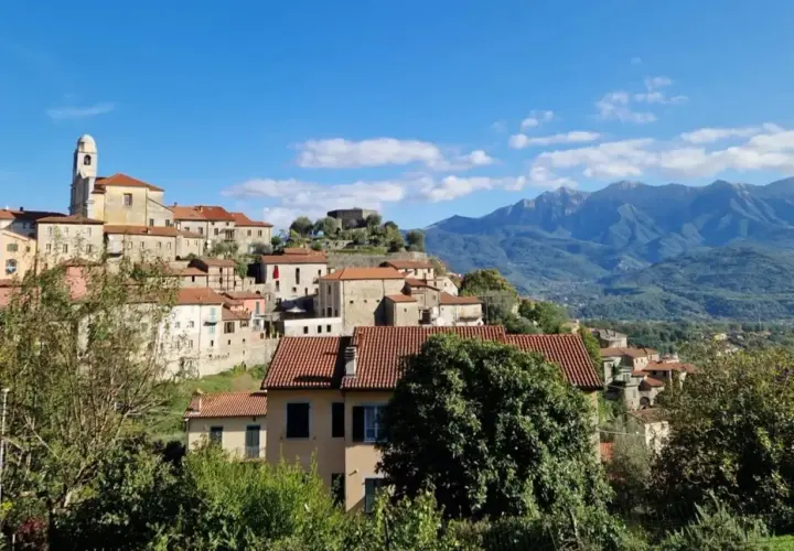 Panoramica di Mulazzo, borgo ligure con case in pietra e tetti rossi, dominato da un castello e con montagne sullo sfondo. Cosa vedere in questo incantevole paese.