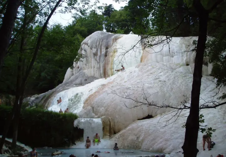 Cascate di travertino a Santa Fiora Terme, con persone che si rilassano nelle acque termali.
