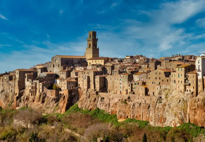 Il centro storico di Pitigliano, arroccato su una rupe tufacea, con le sue case antiche e la torre campanaria che domina il paesaggio.