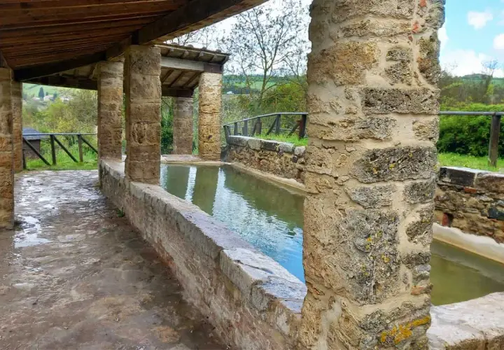 Antiche vasche d'acqua nel centro storico di San Casciano dei Bagni, con colonne in pietra e tettoia in legno.