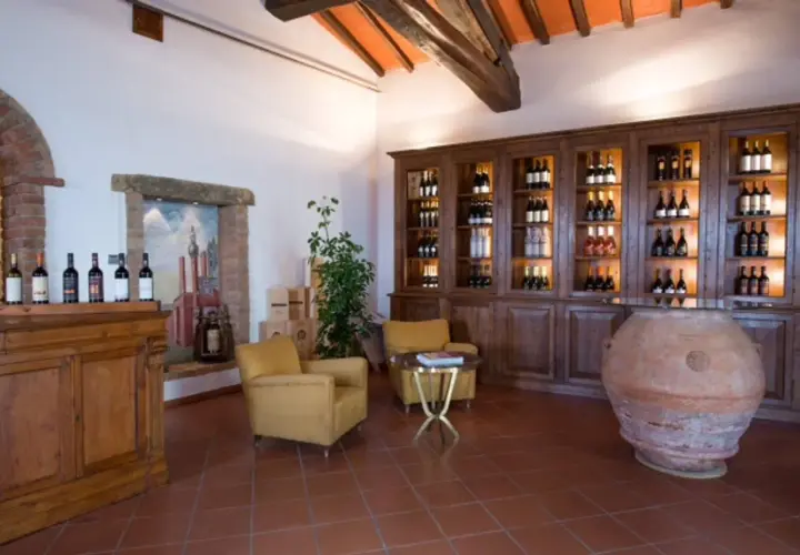 Interno accogliente della cantina Melini, con bottiglie di vino esposte su scaffali in legno e un'antica anfora.
