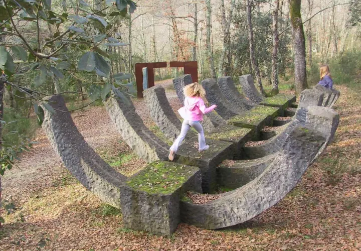 Bambini giocano su una scultura in pietra nel **Chianti Sculpture Park**.