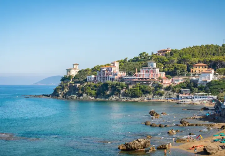 Panorami mozzafiato di Castiglioncello, Italia, con ville storiche affacciate sul mare turchese e una spiaggia animata.
