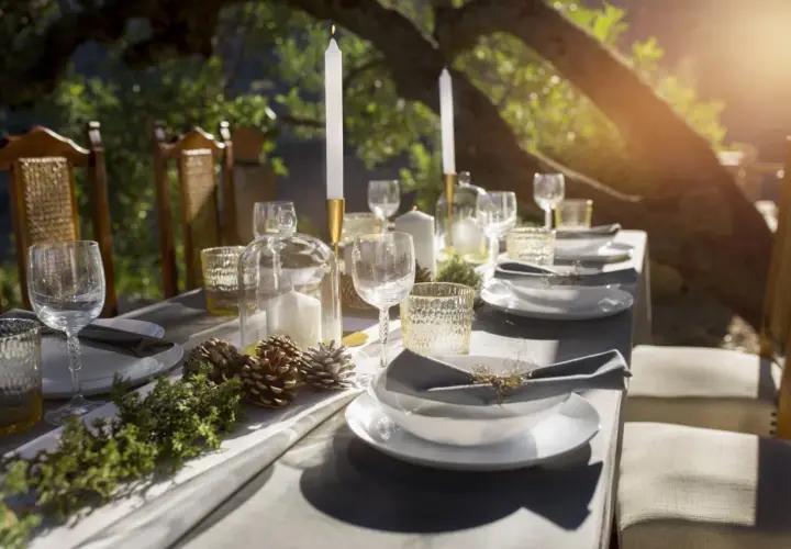 Tavola apparecchiata all'aperto con candele, pigne e rami, evocando un'atmosfera rustica e raffinata, perfetta per una cena nelle cantine di Firenze.