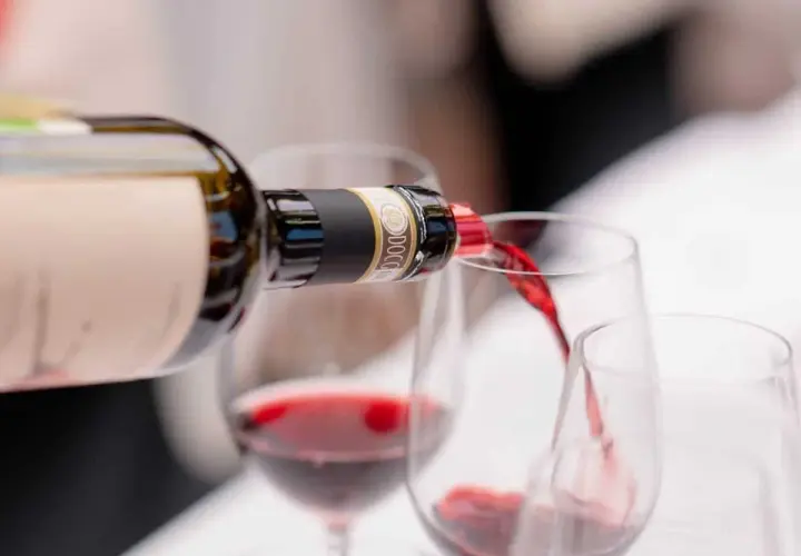 Versando vino rosso da una bottiglia in calici, un'esperienza dei migliori vini Chianti.