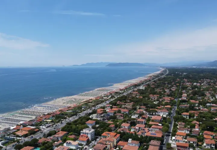 Vista aerea della costa toscana, dove si trova Forte dei Marmi, con spiagge attrezzate, mare blu e un fitto tessuto urbano.