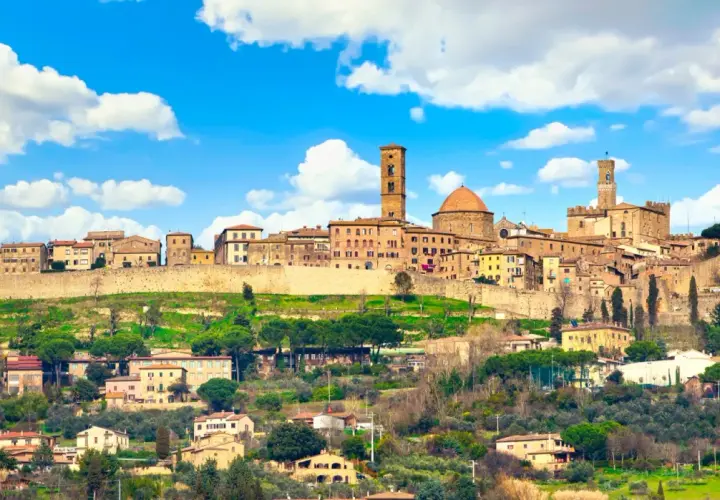 Panoramica di Volterra, con torri medievali e case in pietra su una collina verde. Molte cose da fare a Volterra, tra cui esplorare il centro storico.