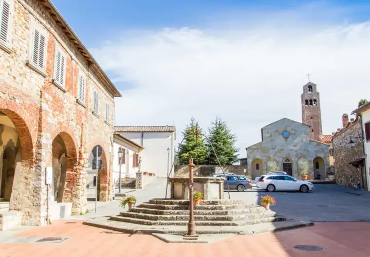 Piazza di Civitella Val di Chiana con pozzo antico, chiesa romanica e case in pietra.