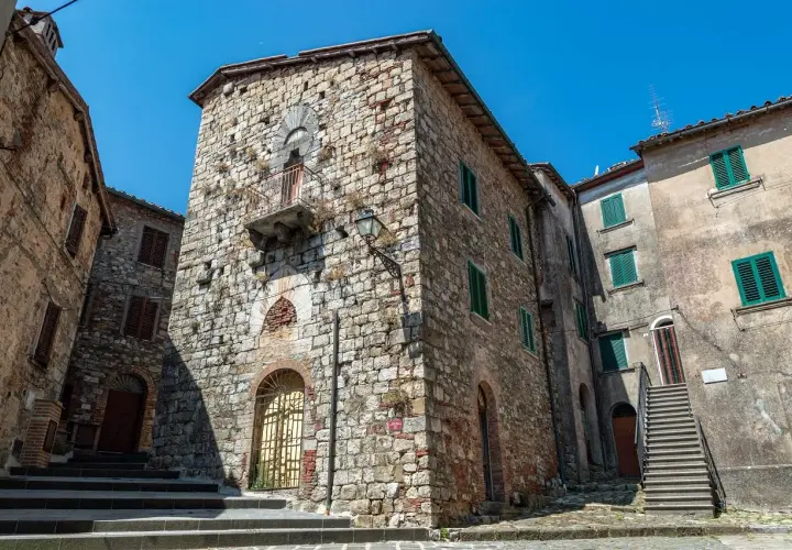 Antiche case in pietra a Montieri, cosa vedere: un vicolo con scale, balcone e finestre verdi.